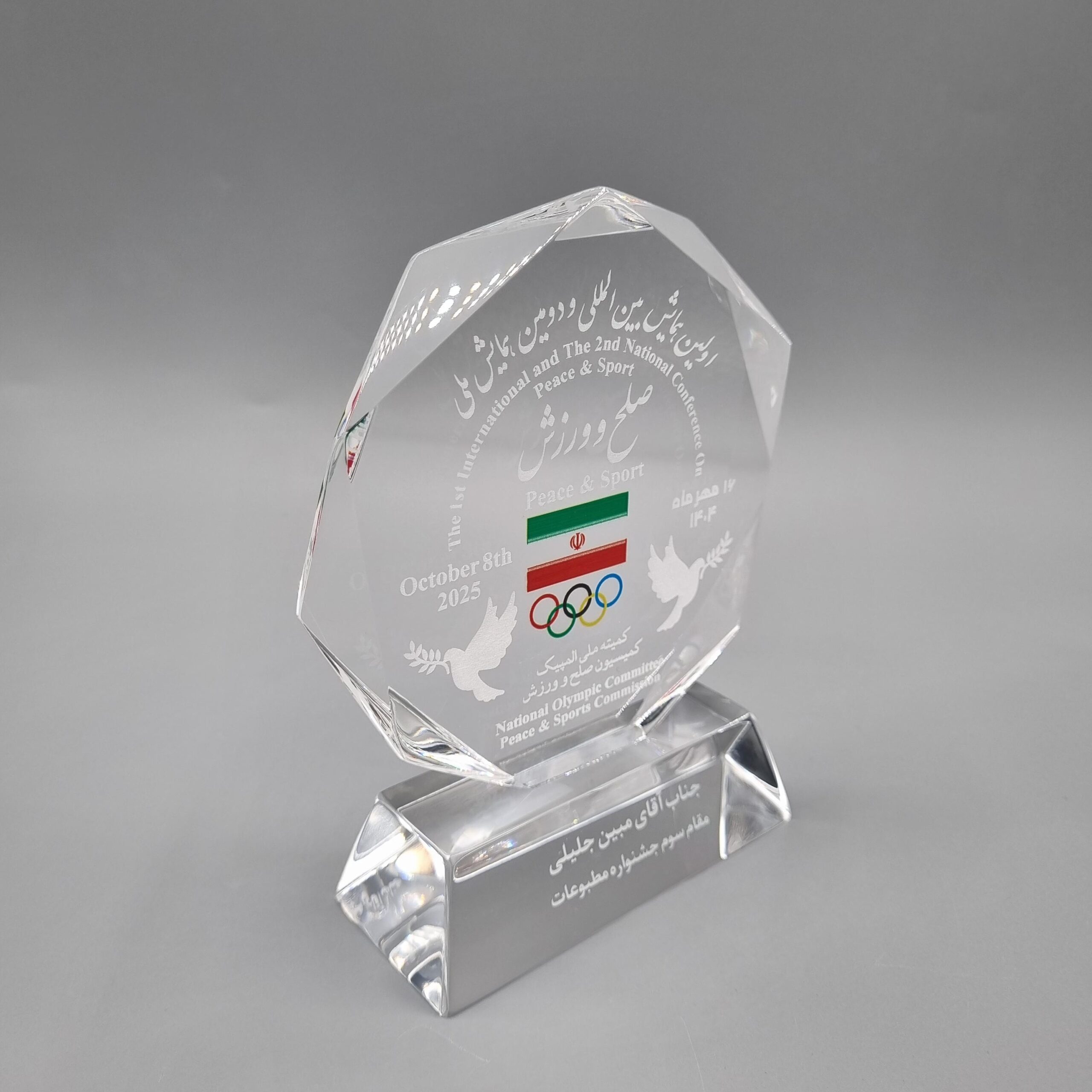 تندیس صلح و ورزش کمیته بین المللی المپیک – 1404 این تندیس بدنه و پایه اش از جنس پلکسی گلاس می باشد . ویژگی مهم و خاصش این است که متن و تصویر در داخل پلکسی گلاس حکاکی شده است . با تراش های الماسه ای که در دو طرف بدنه انجام گرفته زیبایی کار بسیار بیشتر شده و شکوه و وقار تندیس را بالا برده است . پایه پلکسی گلاس که بصورت ذوذنقه ای تراش خورده در هماهنگی کامل با بدنه می باشد . تندیسی شکیل ، زیبا و باشکوه برای ارائه در مراسمی رسمی و پر شکوه